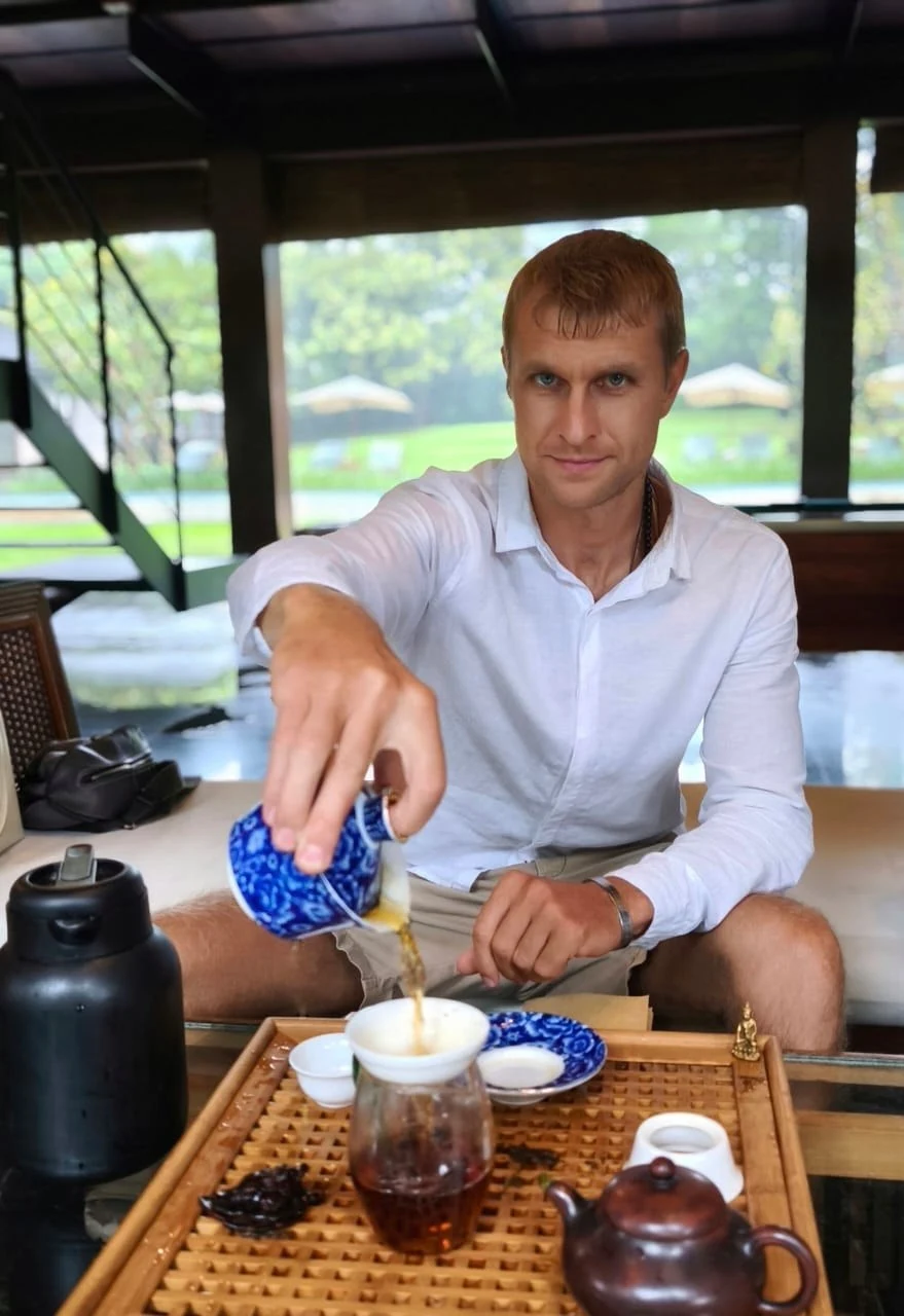 Мужчина наливает чай в стеклянный кувшин на чайном подносе